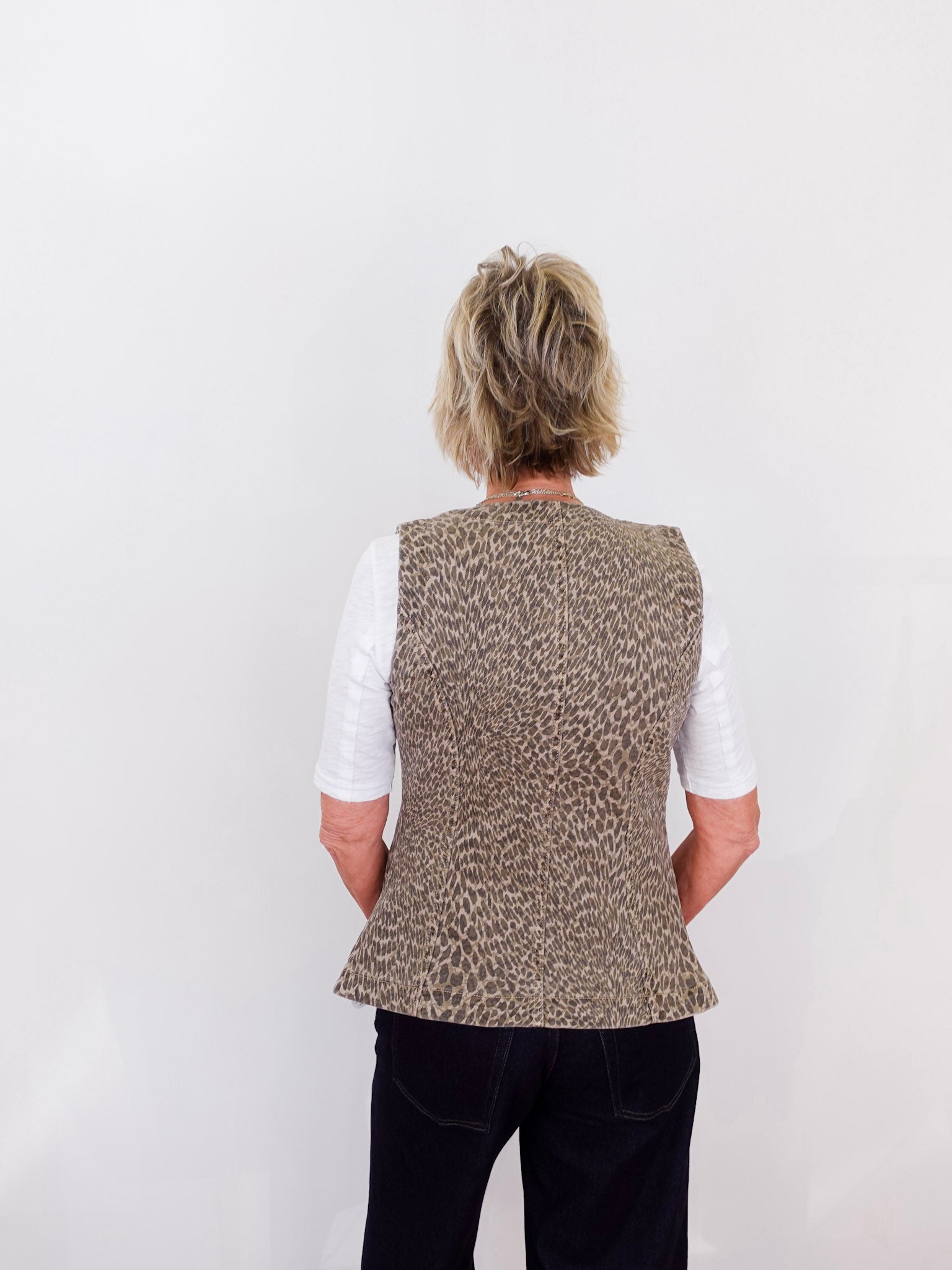 Person wearing a patterned vest over a white shirt on a plain background