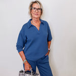 Woman wearing Liverpool pacific blue V-neck popover sweatshirt with collar standing against a white wall