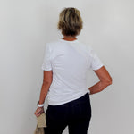 Person wearing a white t-shirt and dark pants against a plain background