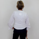 Person wearing a white blouse with puffed sleeves against a plain background
