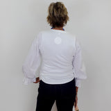 Person wearing a white blouse with puffed sleeves against a plain background