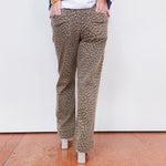 Person wearing leopard print pants with a white wall background