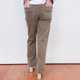 Person wearing leopard print pants with a white wall background