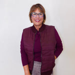 Woman wearing a purple vest over a purple shirt with a white background