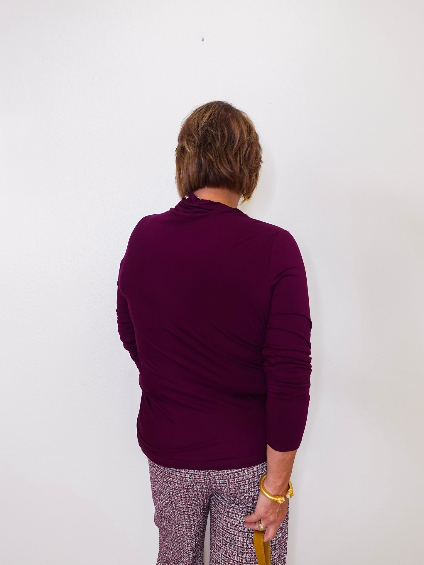 Person wearing a purple sweater and plaid pants against a white background