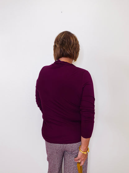 Person wearing a purple sweater and plaid pants against a white background