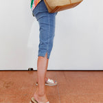 Person wearing blue jeans and white sandals on a tiled floor.