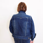 Person wearing a blue denim jacket and pants against a white background
