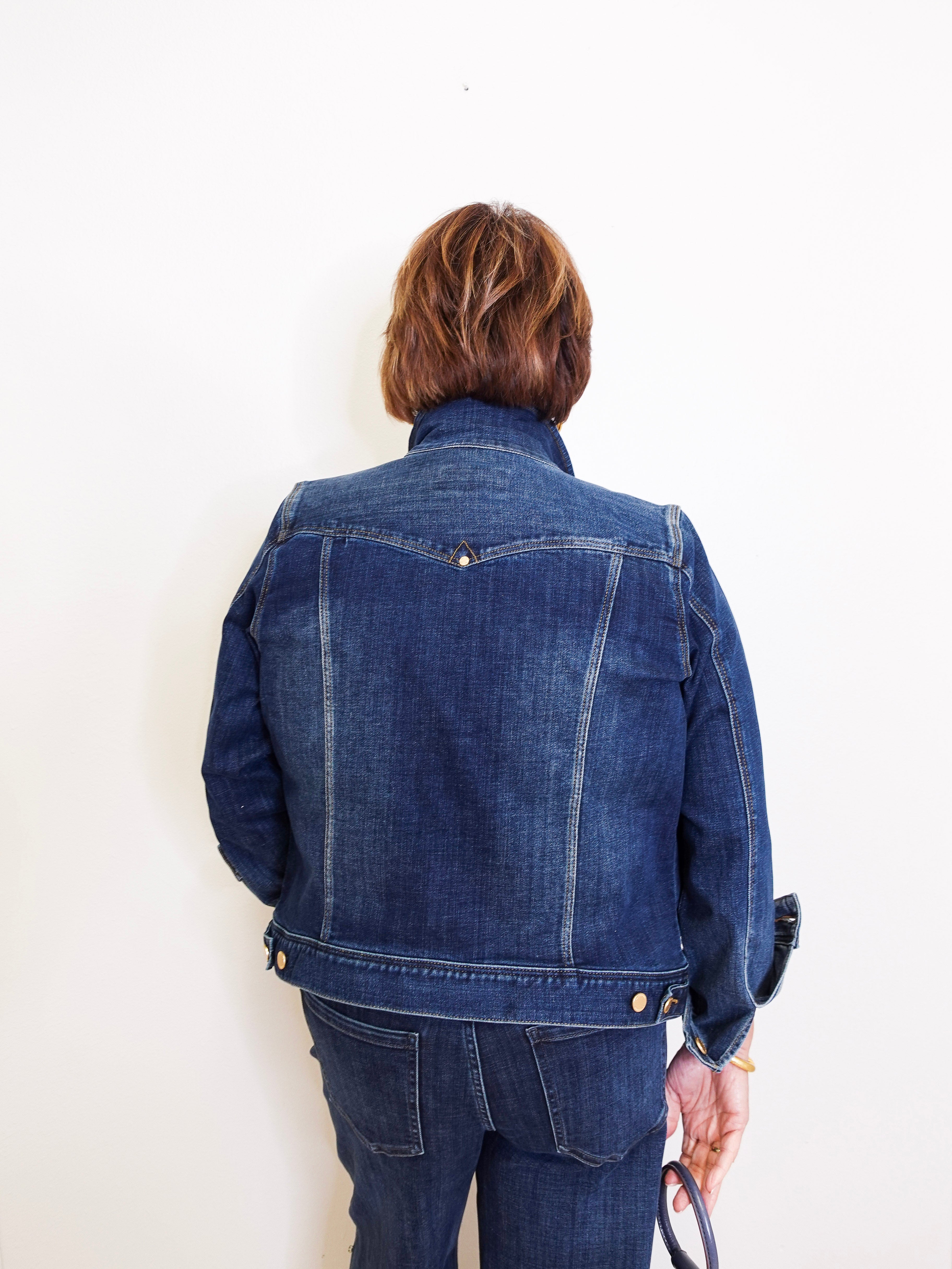 Person wearing a blue denim jacket and pants against a white background