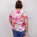 Person wearing a colorful floral shirt and blue jeans against a plain background