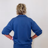 Model showcasing Liverpool pacific blue collar V-neck popover sweatshirt in front of white wall