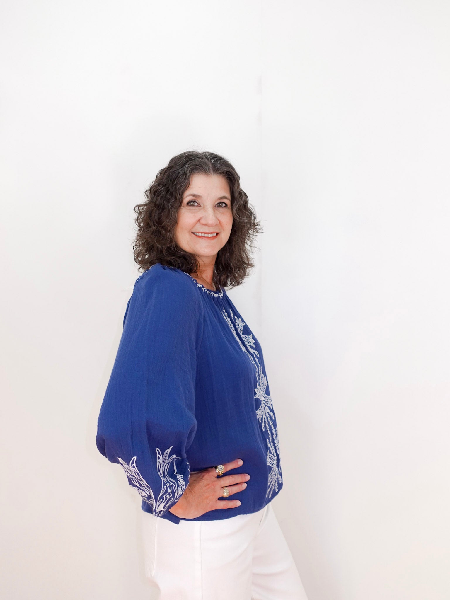 Woman wearing a blue blouse with white patterns on a white background