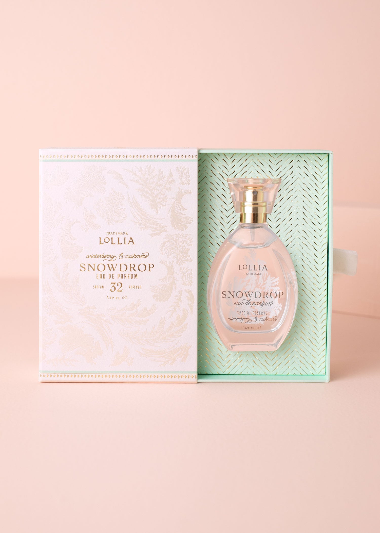 Lollia Snowdrop perfume bottle with packaging on a pink background