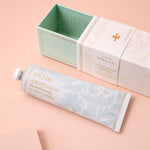 Lollia Snowdrop hand cream with packaging on a peach background