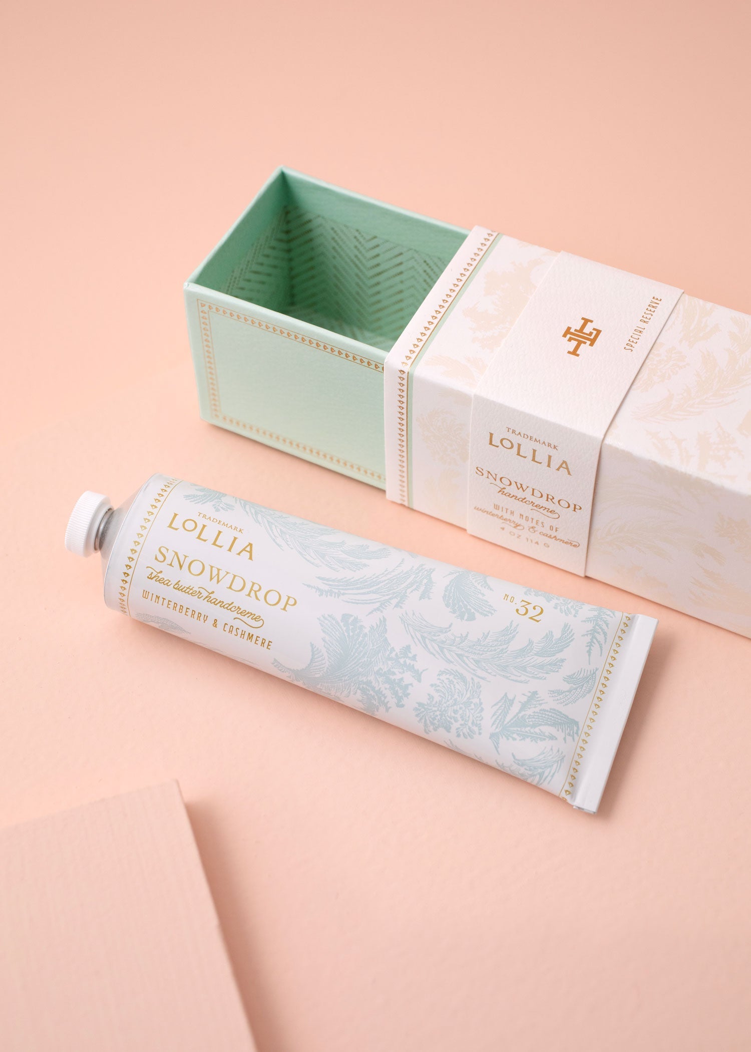 Lollia Snowdrop hand cream with packaging on a peach background