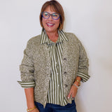 Woman wearing a patterned shirt over a striped blouse with a plain background
