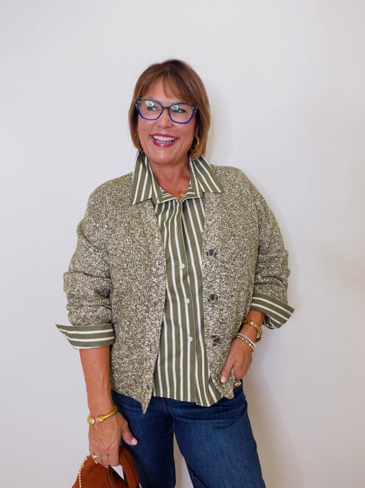 Woman wearing a patterned shirt over a striped blouse with a plain background