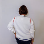 Person wearing a white jacket with colorful  accents against a plain background