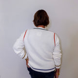 Person wearing a white jacket with colorful  accents against a plain background