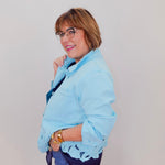 Woman wearing a light blue jacket with lace details on a plain background