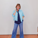 Woman wearing a light blue jacket with lace details on a plain background