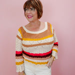 Woman wearing a colorful striped sweater against a pink background
