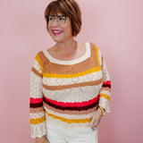 Woman wearing a colorful striped sweater against a pink background