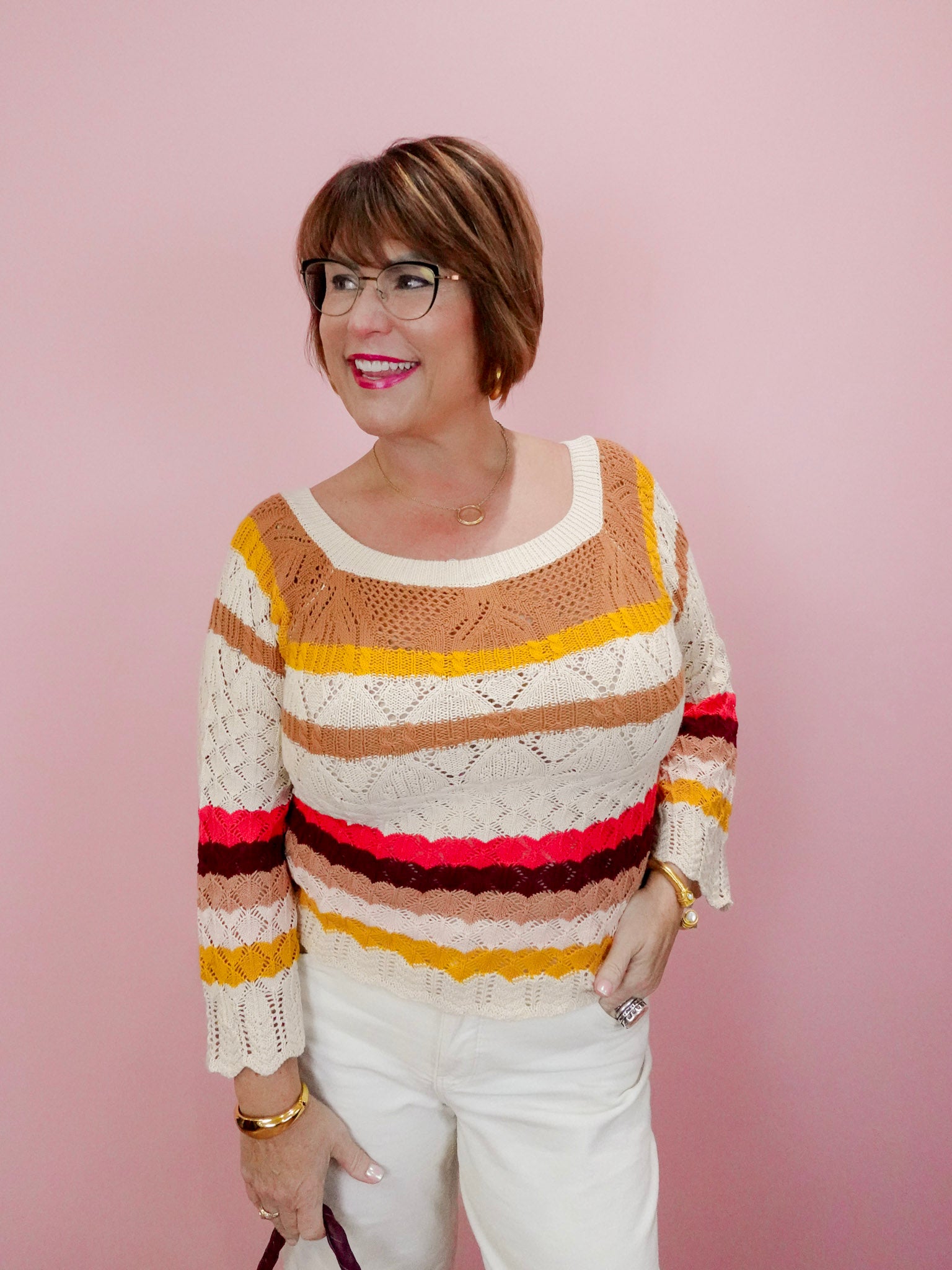Woman wearing a colorful striped sweater against a pink background