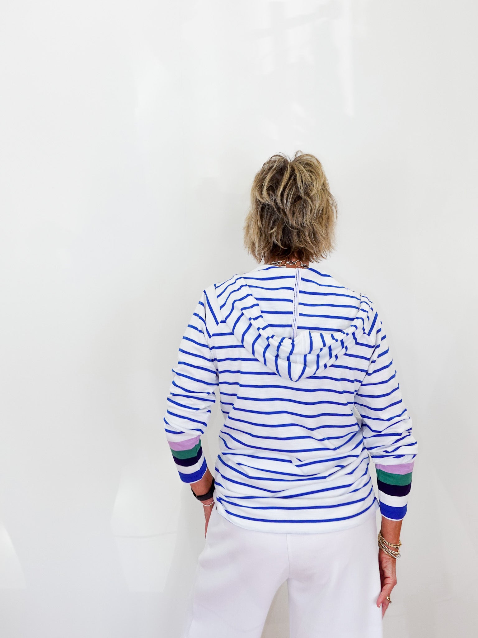 Person wearing a striped shirt with colorful cuffs and hem on a white background