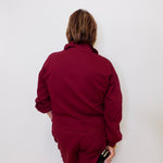 Person wearing a maroon outfit against a white wall