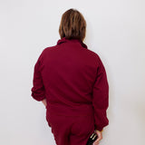 Person wearing a maroon outfit against a white wall