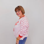 Person wearing a white sweatshirt with red text and blue jeans against a plain background