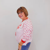 Person wearing a white sweatshirt with red text and blue jeans against a plain background