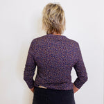 Person wearing a patterned purple jacket against a white background