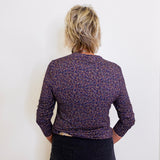 Person wearing a patterned purple jacket against a white background