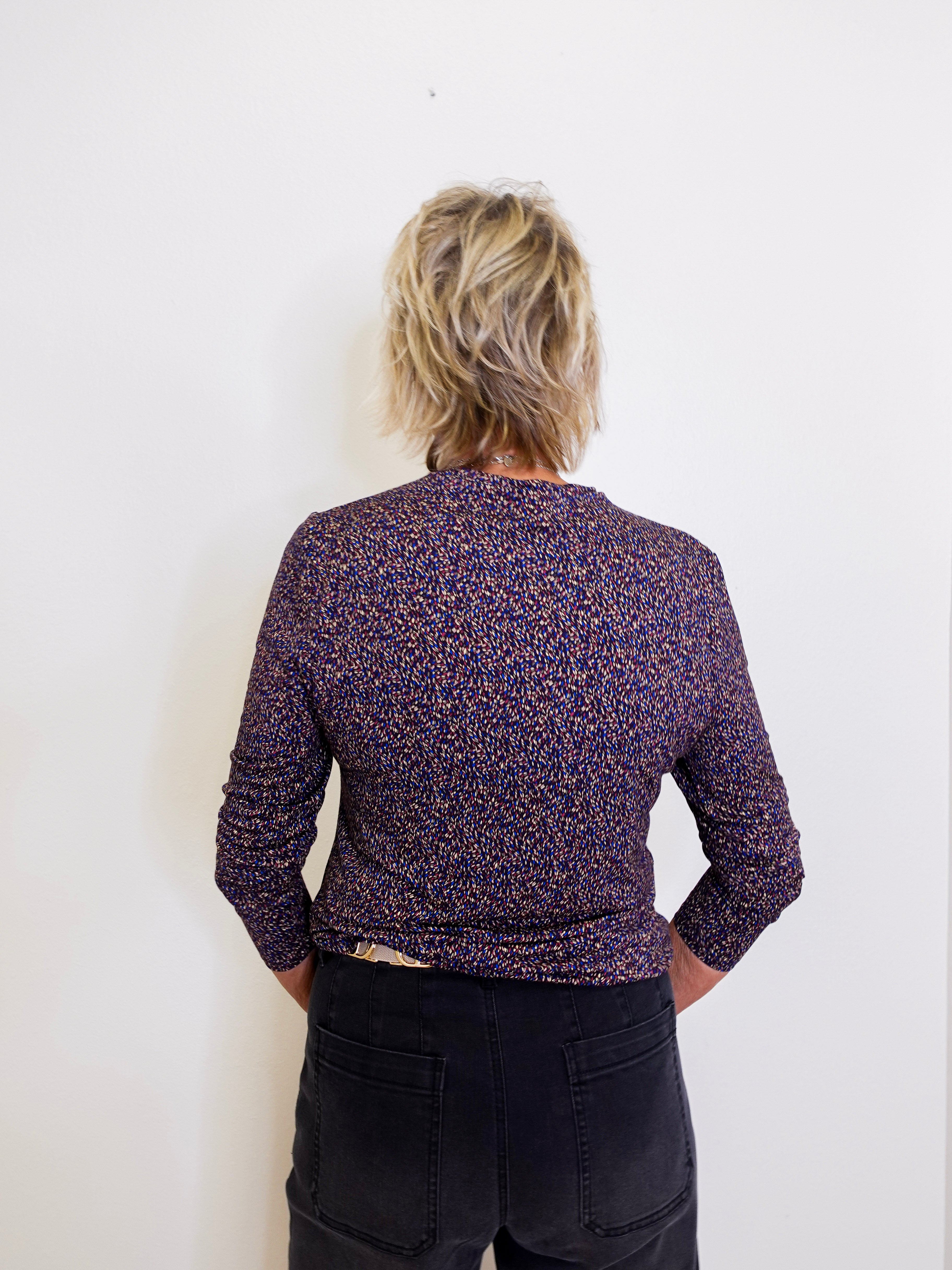 Person wearing a patterned purple jacket against a white background