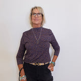 Woman wearing a patterned sweater and black pants against a white background