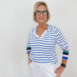 Woman wearing a striped shirt and white pants against a plain background