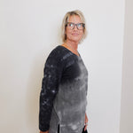 Person wearing a black and gray tie-dye long-sleeve shirt against a white background