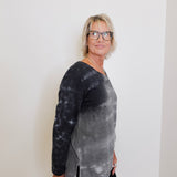 Person wearing a black and gray tie-dye long-sleeve shirt against a white background