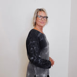 Woman wearing a black and gray tie-dye shirt against a white background