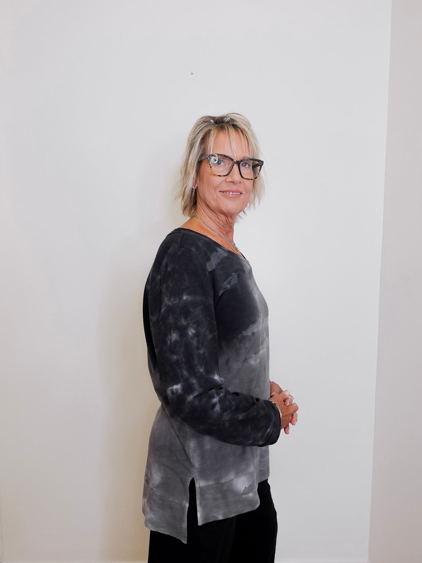 Woman wearing a black and gray tie-dye shirt against a white background