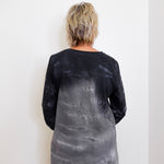Person wearing a black and gray tie-dye long-sleeve shirt against a white background