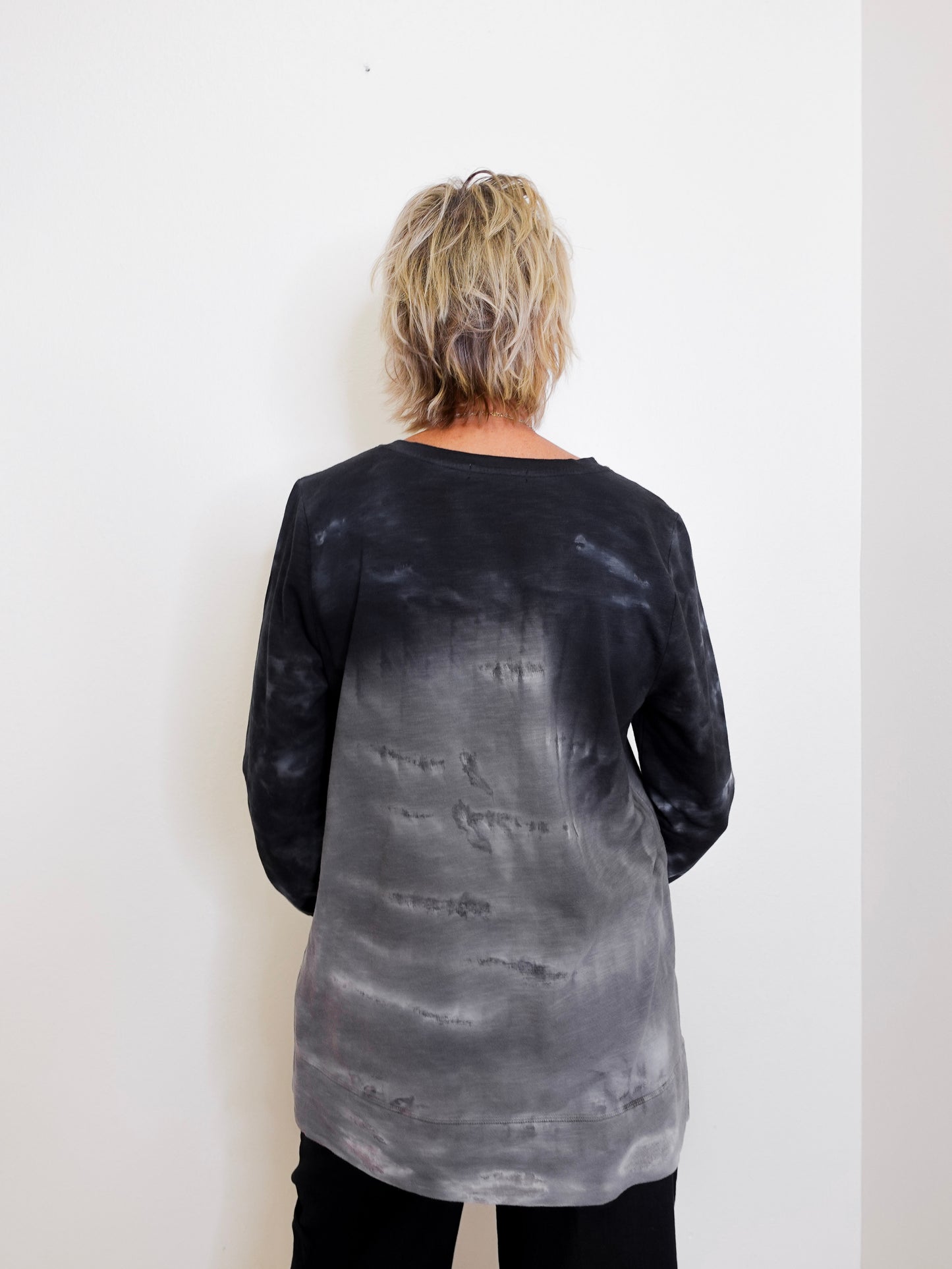 Person wearing a black and gray tie-dye long-sleeve shirt against a white background
