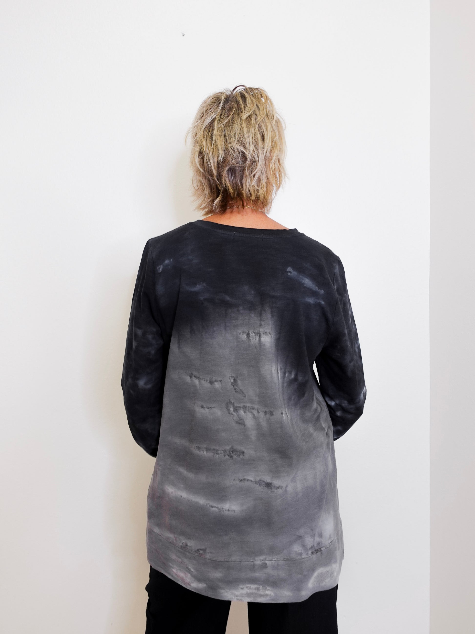 Person wearing a black and gray tie-dye long-sleeve shirt against a white background