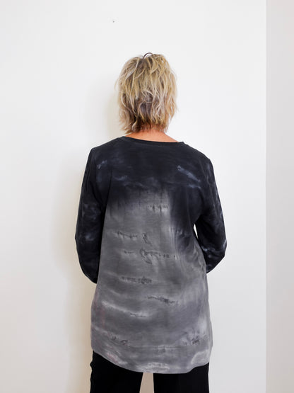 Person wearing a black and gray tie-dye long-sleeve shirt against a white background
