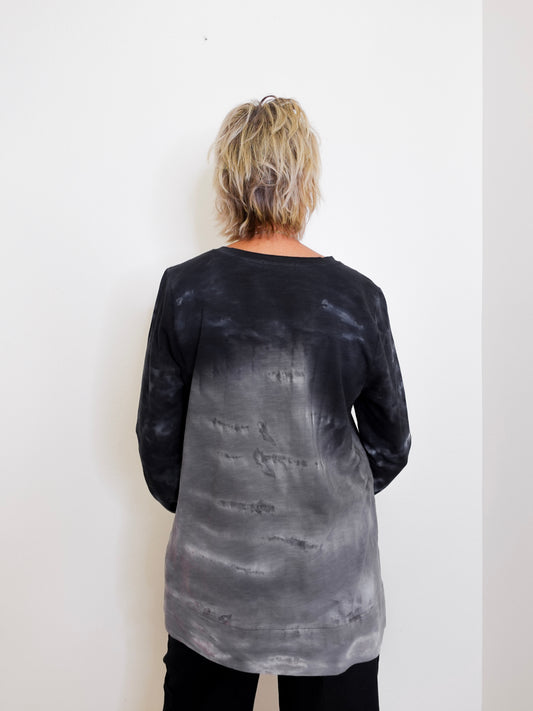 Person wearing a black and gray tie-dye long-sleeve shirt against a white background
