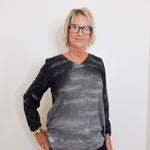 Person wearing a black and gray tie-dye long-sleeve shirt against a white background
