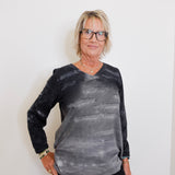 Person wearing a black and gray tie-dye long-sleeve shirt against a white background