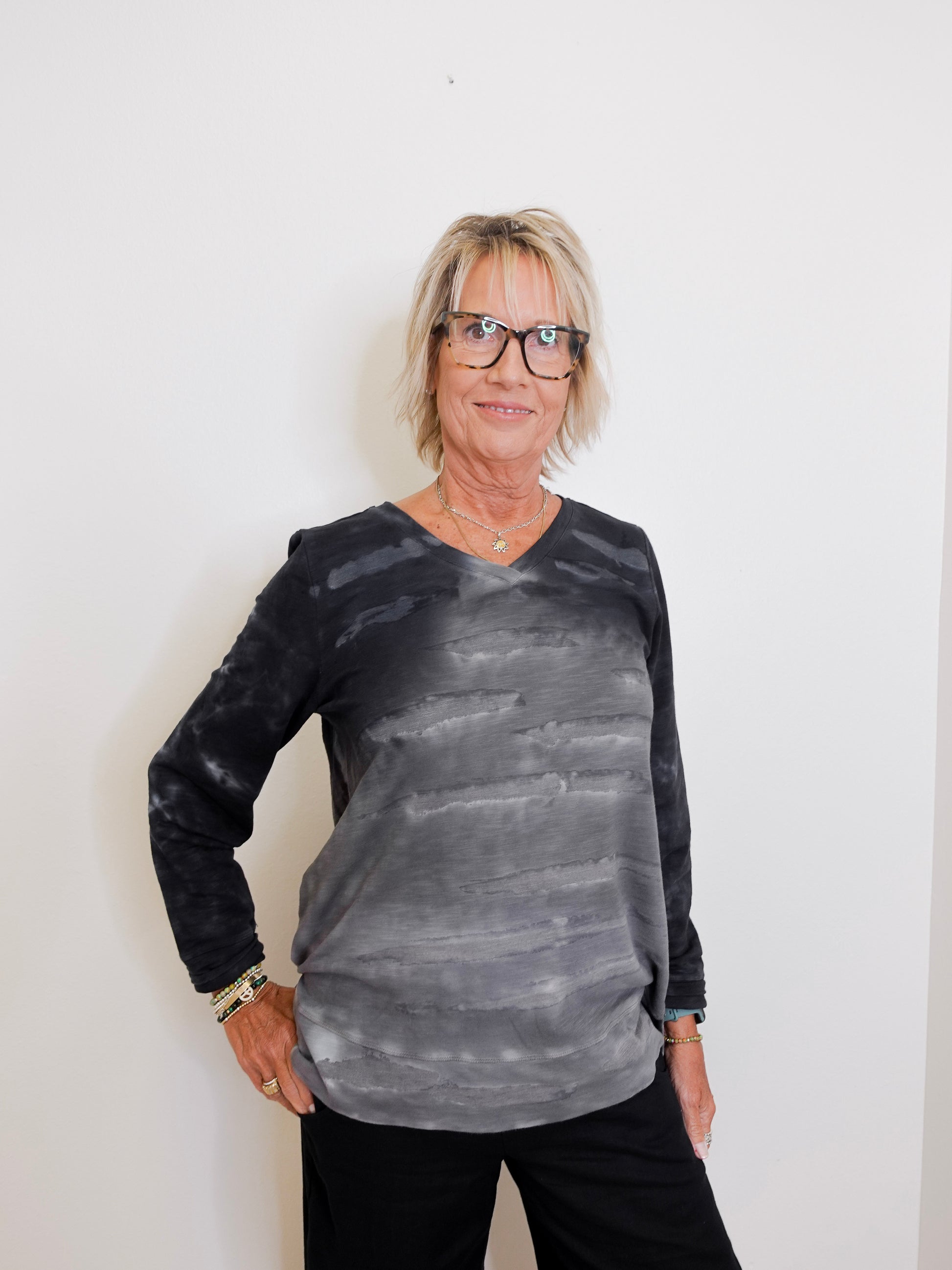 Person wearing a black and gray tie-dye long-sleeve shirt against a white background